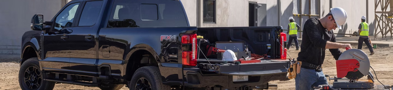 Camionnette Ford sur un chantier avec un travailleur et des outils.